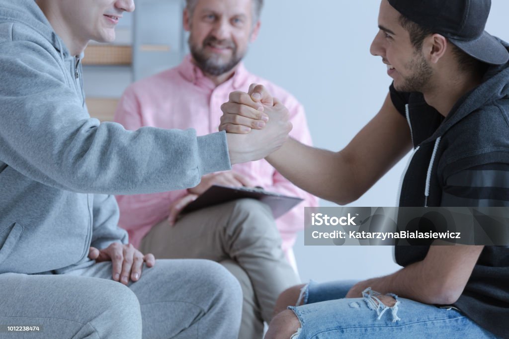 Zwei junge Mann Hand in Hand als eine Geste der Freundschaft während eines Treffens der mediation - Lizenzfrei Schlichtung Stock-Foto