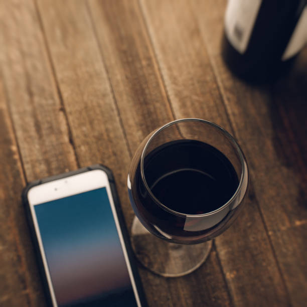 überprüft telefon beim trinken ein glas wein - wine bottle bottle burgundy wine stock-fotos und bilder