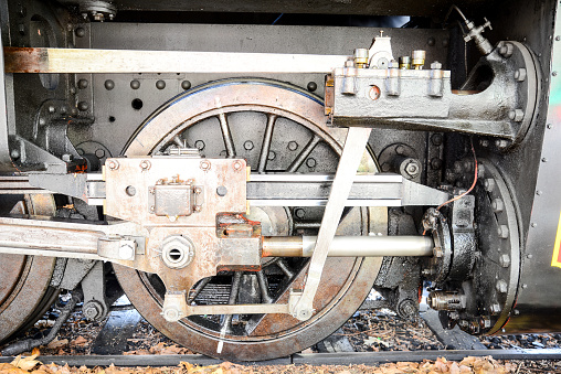 details of steel mechanism, wheels and piston of old steam train locomotive on a railway