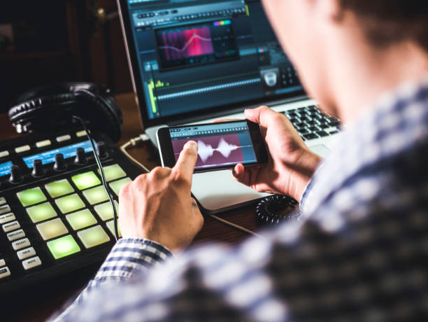 10 Ways to Optimize Your Computer for Music Production 11 close up sound producers hand holding phone and using app to create music in sound recording