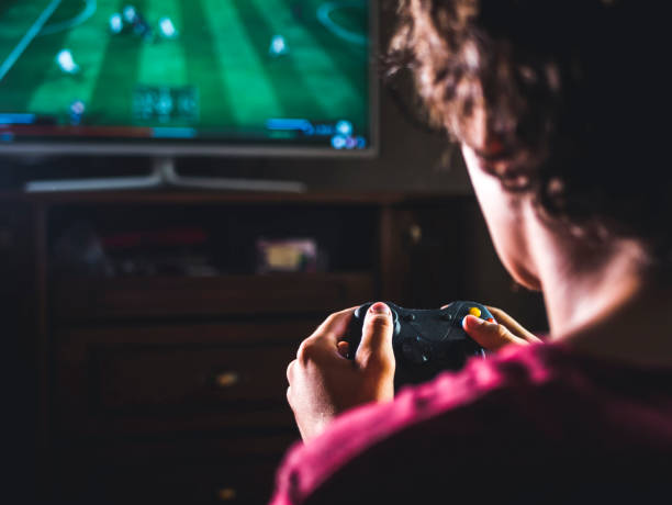 close up young man with joystick controller for console playing sport simulator video game on large screen
