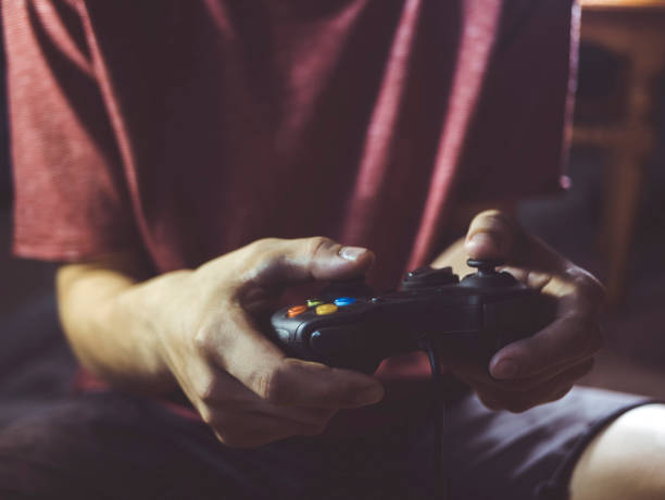 brodaty mężczyzna trzymający kontroler joysticka gier wideo w rękach przed ciałem w domu w nocy - video game gamepad black isolated on white zdjęcia i obrazy z banku zdjęć