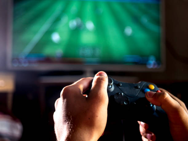 junger mann mit joystick-steuerung für konsole spiel sport simulator video auf großleinwand hautnah - spielsteuerung fotos stock-fotos und bilder
