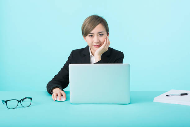 istock business woman wearing black suit using laptop computer with happy face 1012260178