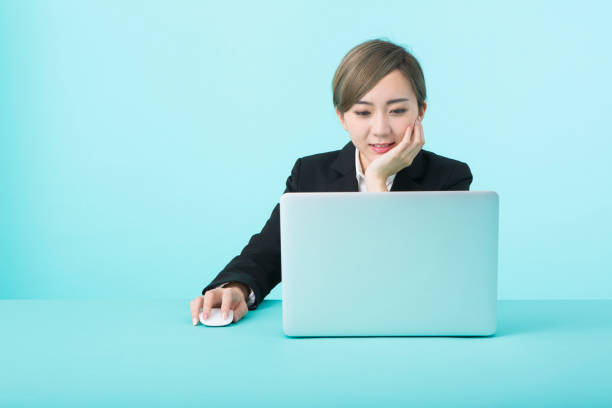 istock business woman wearing black suit using laptop computer with happy face 1012260218