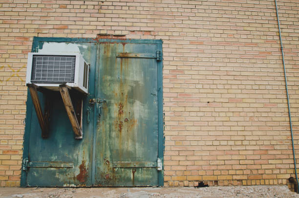 A old green faded door with an ac.