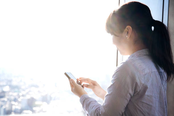 istock Business woman using a smart phone at skyscraper 1012273242