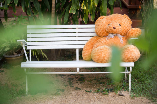 istock Alone cute teddy bear sitting on wood and snow is falling,white snow background blur stlye. 1012275684