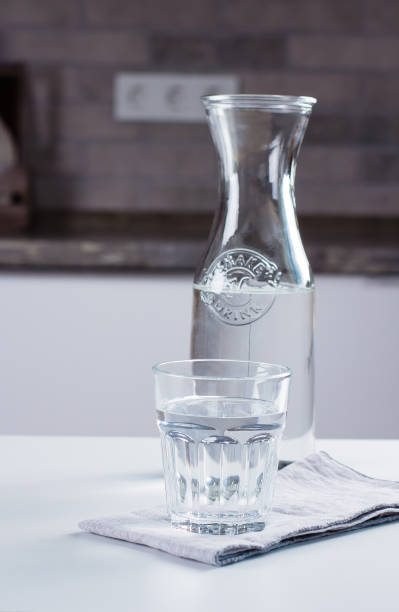 istock Glass of pure water and bottle on kitchen table. Clean Concept 1012289632