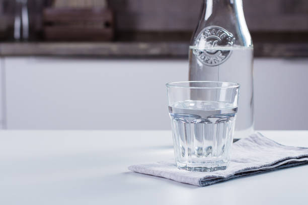 istock Glass of pure water and bottle on kitchen table. Clean Concept 1012289836