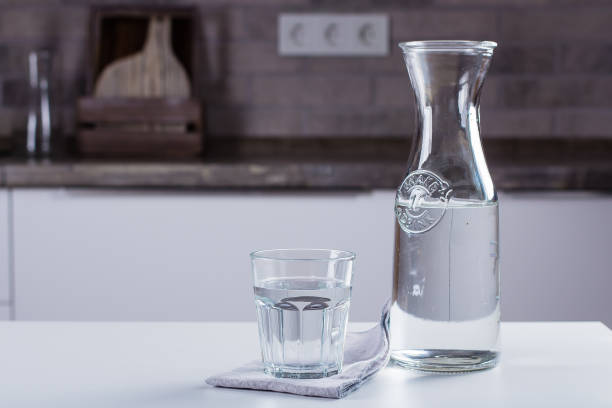 istock Glass of pure water and bottle on kitchen table. Clean Concept 1012290190