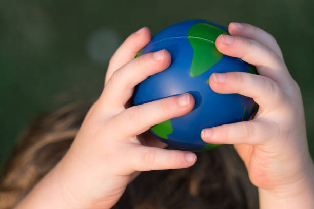 istock Holding up high planet earth sphere being held by small toddler hands above head 1012294122