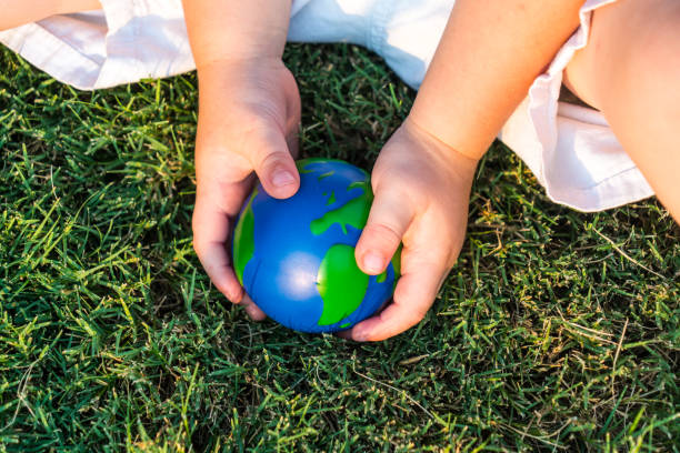 istock planet earth sphere being held by small toddler playing in grass 1012294146