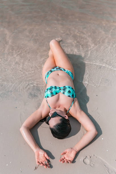 istock Woman on the beach lying on the sand 1012320892