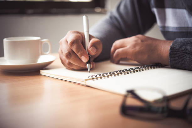 istock The hand of a man holding a pen and taking notes in a notebook. 1012323796