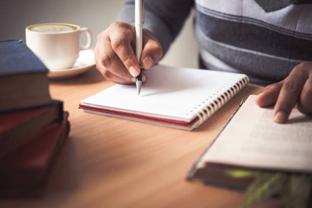 istock The hand of a man holding a pen and taking notes in a notebook. 1012323862