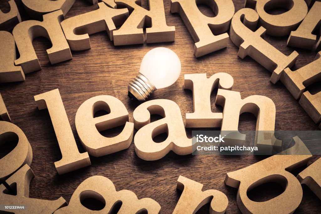 Learn and Bulb LEAEN word by wood letters with glowing light bulb Learning Stock Photo