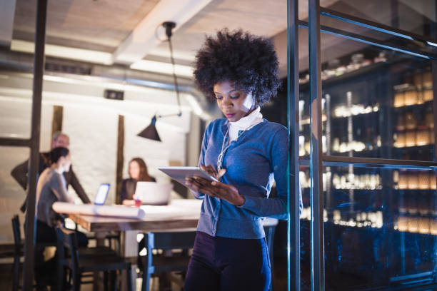 istock Female Leaders. Young African-American woman architect using digital tablet in front of architecture studio. 1012364022