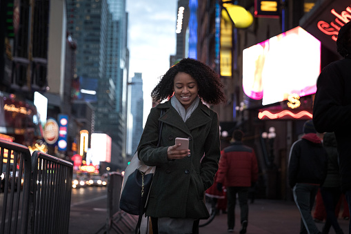 Young woman in the city streets in downtown New York texting on mobile