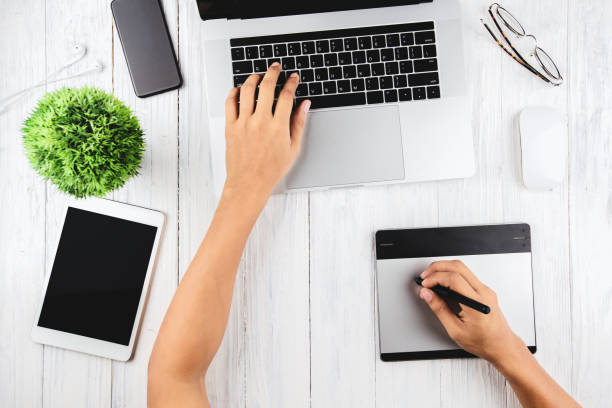 istock graphic designer using laptop and graphic tablet on top view 1012372098