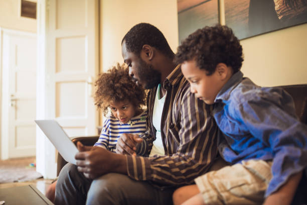 istock Kids having fun at home, playing with their father, using laptop 1012381204