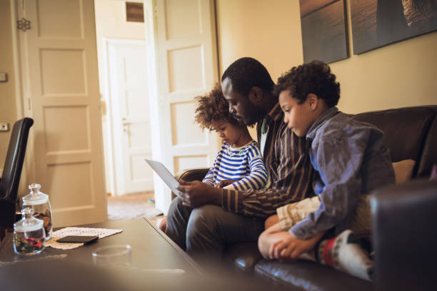 istock Kids having fun at home, playing with their father, using laptop 1012381214