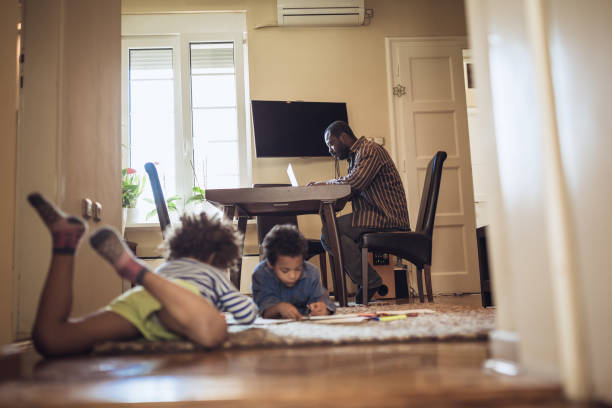 istock Kids playing while their father working at home 1012381234