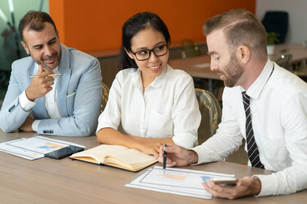 istock Three smiling business people working with diagrams at desk 1012390336