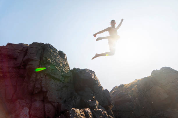 istock Young men jumping off cliff into sea 1012401666