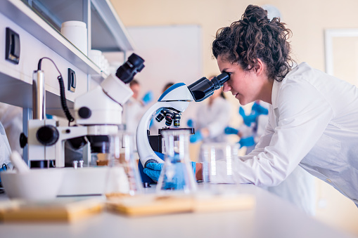 Scientist in lab doing research and using lab machines, test tubes, microscope and every laboratory equipment