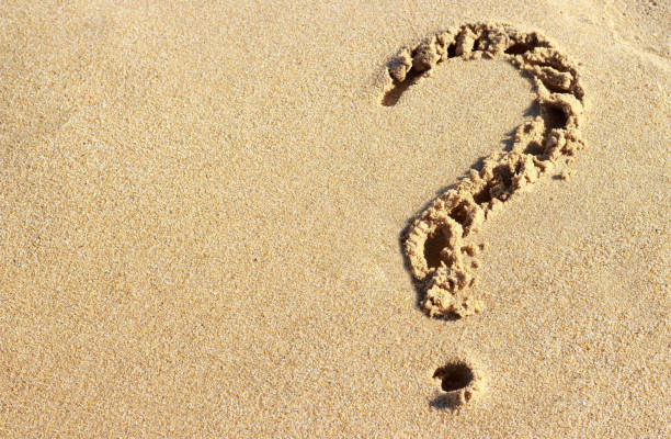 istock question mark drawn on a sandy beach, close-up, top view 1012417168