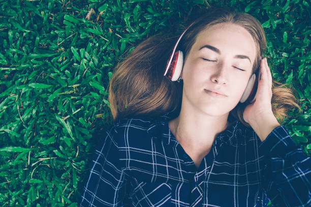 istock Content Young Lady Listening to Music on Grass 1012420024
