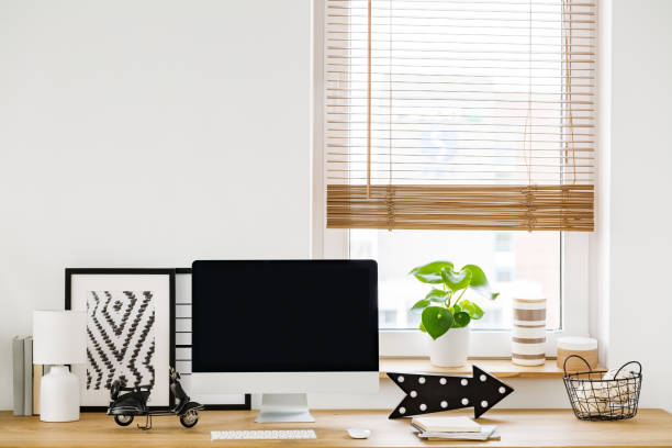 istock Close-up on a minimalist, white workspace interior by a window with a modern computer and simple decorations on a wooden desk 1012423370