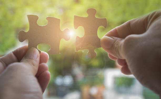 istock Two hands trying to connect couple jigsaw puzzle piece with sunlight effect. Business solutions, success and strategy concept 1012423614