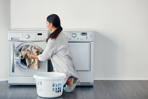 Shot of a young attractive woman doing her laundry at home