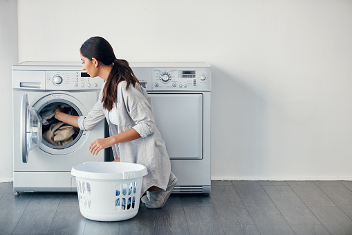 Shot of a young attractive woman doing her laundry at home