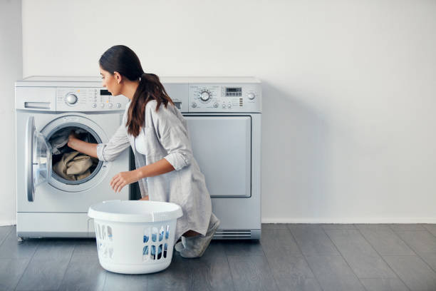 I do my laundry once a week Shot of a young attractive woman doing her laundry at home utility room stock pictures, royalty-free photos & images