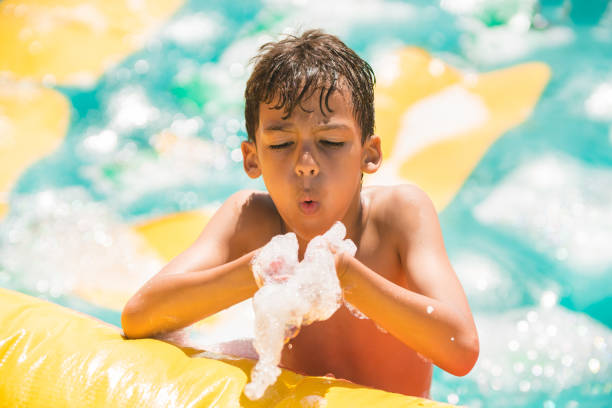 istock Boy blowing foam in the inflatable pool 1012436482