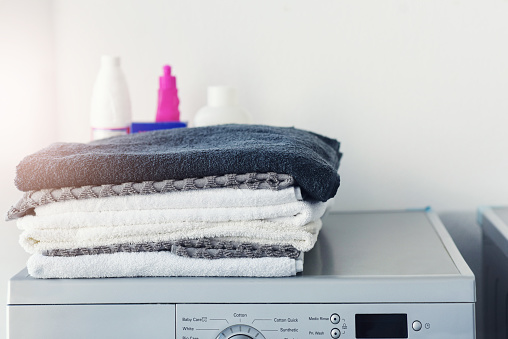 Shot of a pile of linen folded on top of a washing machine at home