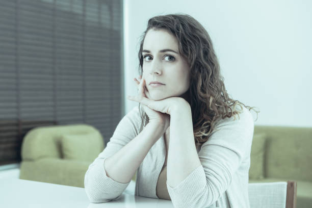 istock Serious Pretty Woman Sitting at Table at Home 1012438908