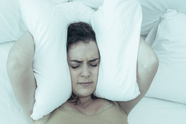 istock Dissatisfied Lady Covering Ears With Pillow in Bed 1012439110