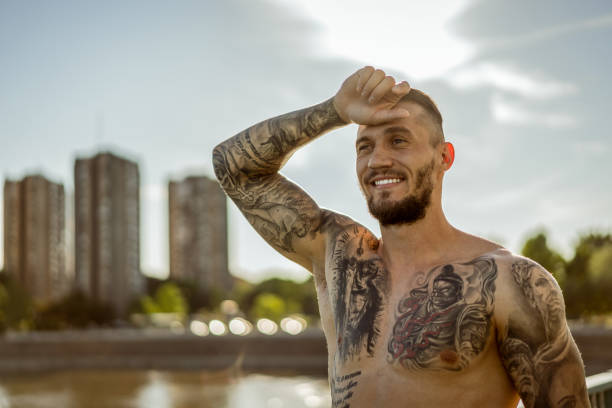 istock Young handsome tattooed man resting after training hard outdoors 1012460436