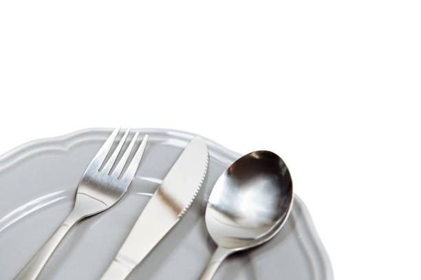 istock Plate with a silver fork, spoon and a knife isolated on white background 1012470870