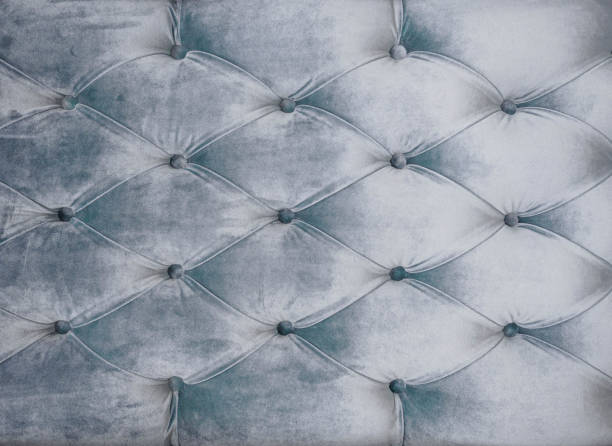 istock Couch-type velours screed tightened with buttons. Gray chesterfield style quilted upholstery backdrop close up. Capitone pattern texture background 1012478444