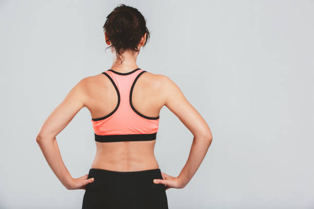 Rearview shot of a sporty young woman posing against a grey background