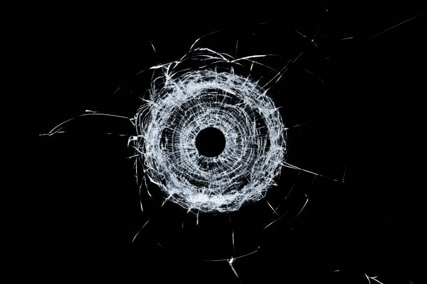 istock Broken glass single bullet hole in glass isolated on black 1012509596