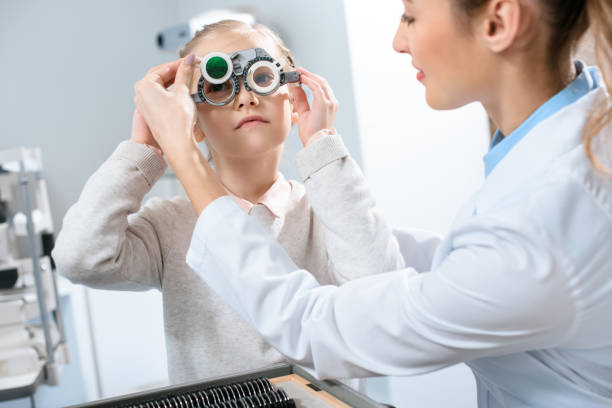 istock female oculist examining kid eyes with trial frame and lenses 1012509830
