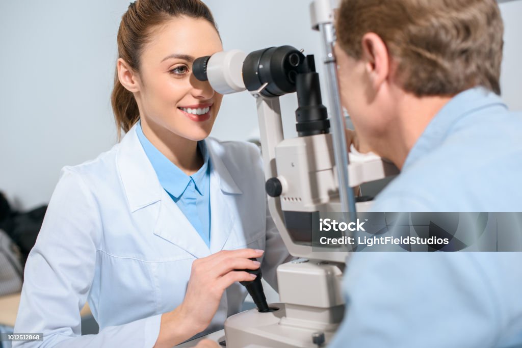 professional optician examining man with modern optical equipment Ophthalmologist Stock Photo