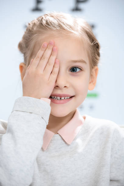 istock smiling little kid closing eye with eye chart behind 1012513122