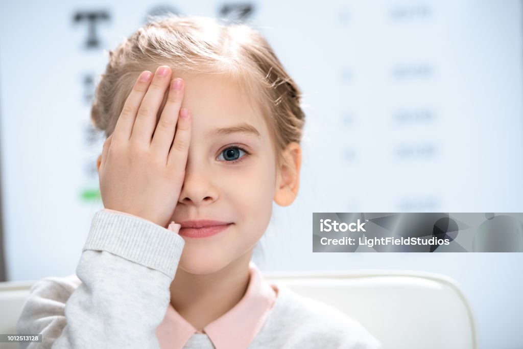 petit enfant fermer le œil avec l’examen de la vue derrière - Photo de Enfant libre de droits